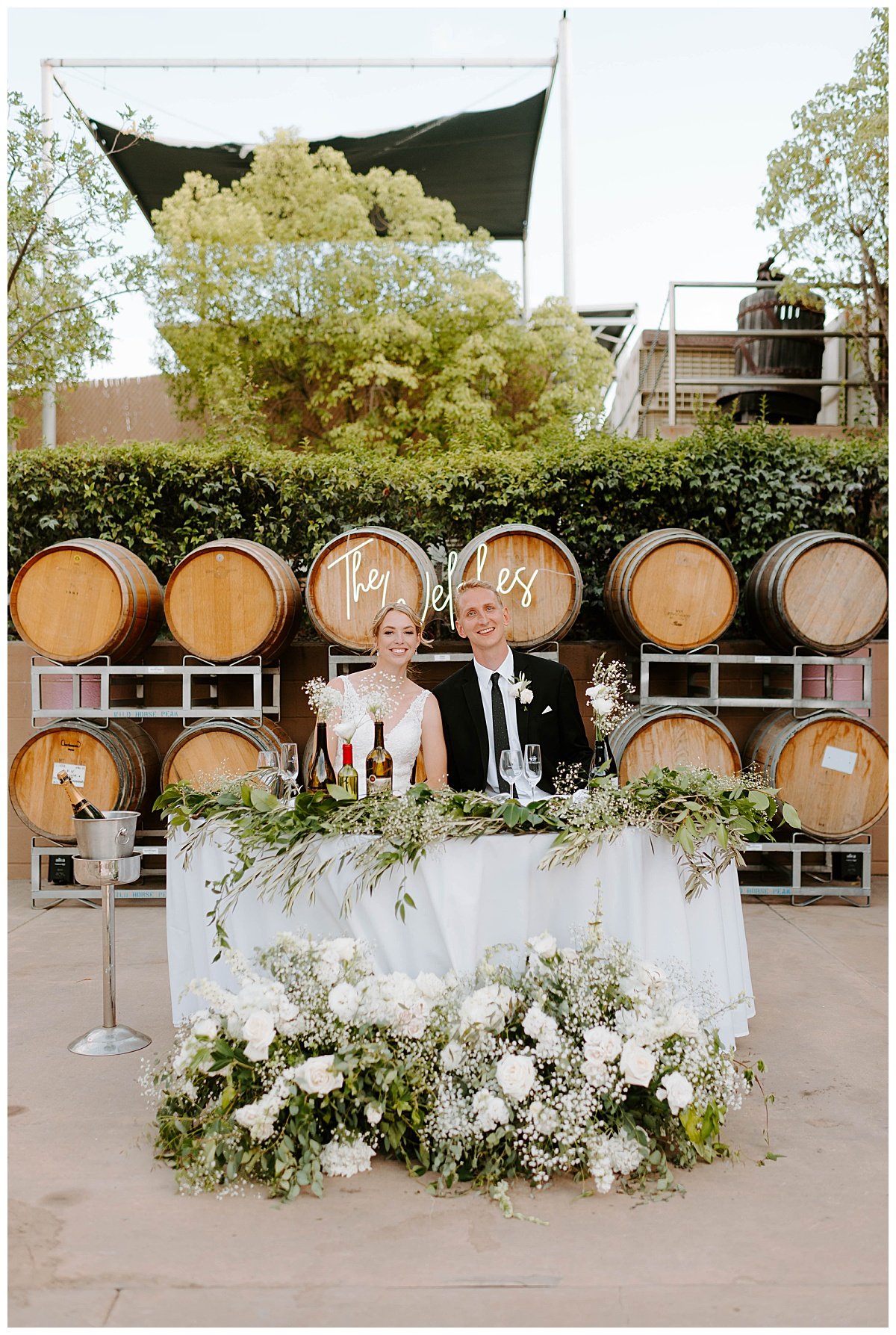 bride and groom sweetheart table in front of wine barrels for wedding at the south coast winery